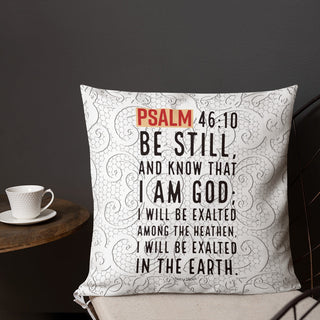 Square Psalm 46:10 pillow with gray paisley pattern beside coffee cup