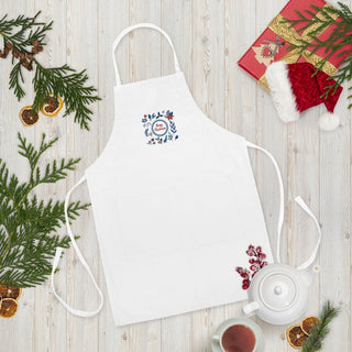 White Christmas wreath apron beside holiday greenery and teapot