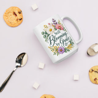 White Still Blooming by Grace mug with colorful flowers, beside a cookie, spoon, and sugar cubes.