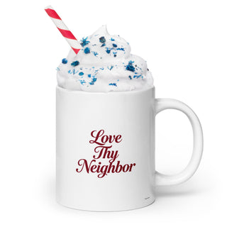 White Love Thy Neighbor mug with burgundy script, filled with a decorated cold drink.