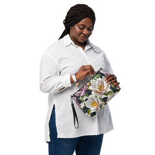 Bed of Roses crossbody bag with cream flowers, purple roses and black trim; held by a model in a white shirt.