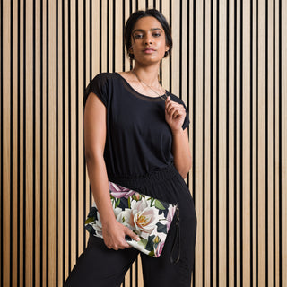 Bed of Roses crossbody bag with cream flowers, purple roses and black trim; worn by a model in black.