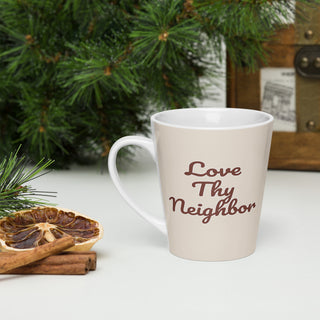 Cream-colored Love Thy Neighbor latte mug with burgundy script, beside greenery and cookies.