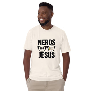 A man wearing a cream-colored t-shirt with a black graphic that reads 'NERDS FOR JESUS' with glasses and an open book illustration, paired with khaki pants, against a plain white background.