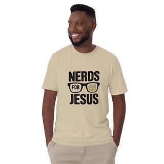 A smiling man wearing a beige crewneck t-shirt with a black graphic that reads 'NERDS FOR JESUS' with glasses and an open book illustration, paired with khaki pants, against a plain white background.