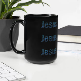 Black mug on a desk with a plant and notebook in the background