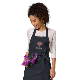 Navy God Is Love apron with floral heart embroidery, worn by a model holding purple flowers.