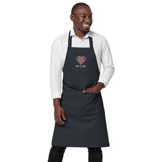 Front view of a model wearing the navy God Is Love apron with one hand in its front pocket.