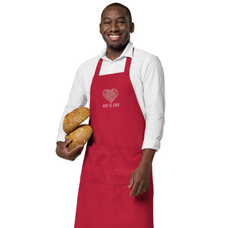 Red God Is Love apron with floral heart embroidery, worn by a model holding bread.
