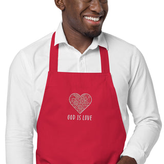 Close-up of floral heart embroidery and God Is Love lettering on a red apron worn by a model.
