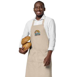 Man holding two loaves of bread while wearing the beige Christians For Christ apron.