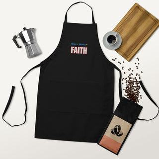 Hope + Works = Faith embroidered apron; black apron laid flat with coffee accessories.