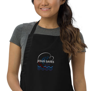 Jesus Saves embroidered apron with waves and a small boat design; black, cropped front on a model.