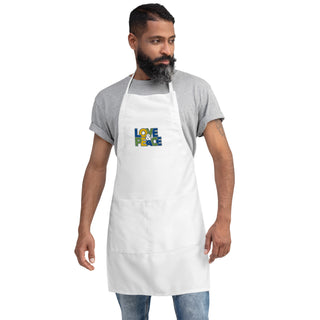 Love & Peace embroidered apron with blue, green, and yellow lettering, white apron on a model, full length.