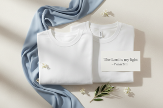 Uplifting, faith-centered product flatlay featuring a hoodie and t-shirt arranged neatly with a Bible verse card (‘The Lord is my light – Psalm 27:1’) next to them. Soft white and light beige backdrop, gentle natural lighting. Include ShellMiddy blue (#1173CE) as a color accent through a ribbon or folded fabric. Clean, modern, premium Christian lifestyle aesthetic suitable for an email signup popup.