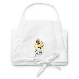 Folded white Amazing Grace apron showing butterfly and floral embroidery with script lettering.
