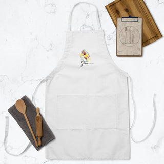White Amazing Grace apron laid flat beside wooden kitchen utensils.