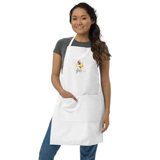 Woman wearing the white Amazing Grace apron with one hand in a pocket.