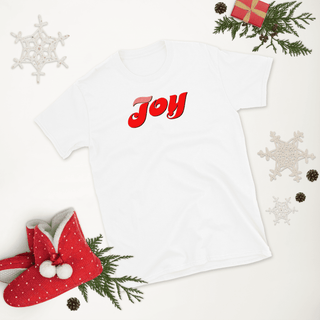 White T-shirt with red Joy script, laid flat with Christmas decorations
